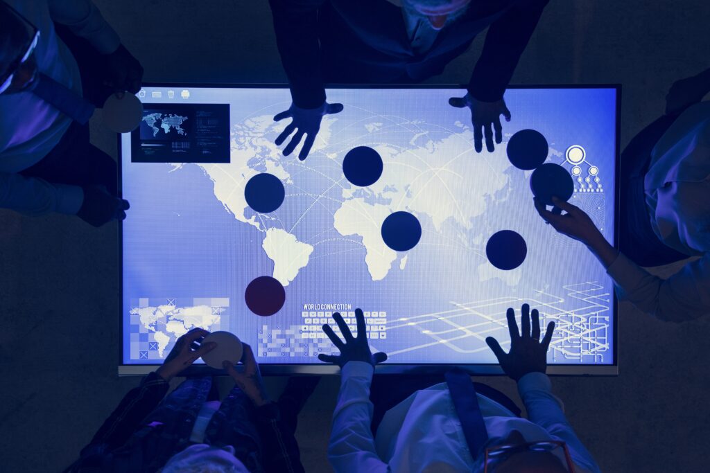 Hands around a blue interactive screen showing multi-touch