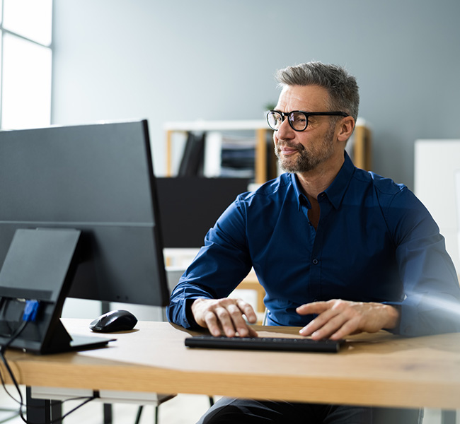 Adult male using computer with High-Speed Internet at a desk inside an office