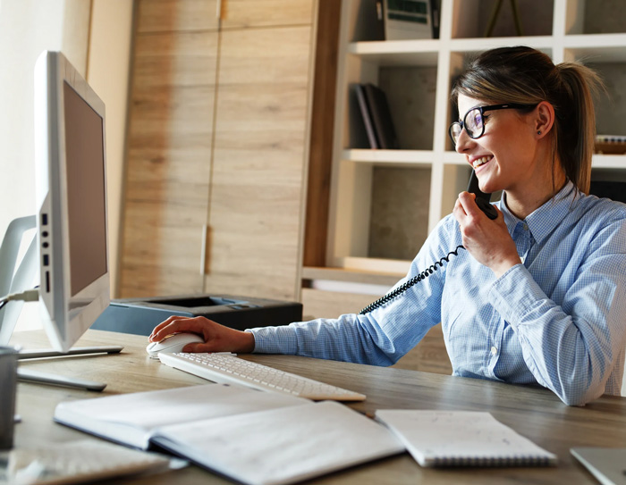 A Woman on the phone while working at a computer