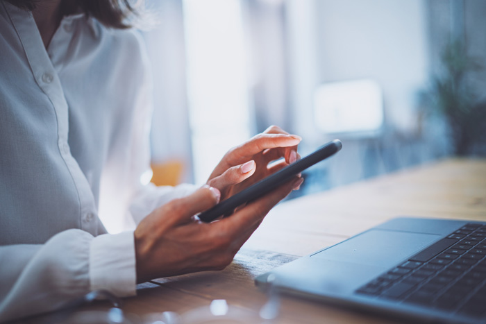 Woman using mobile phone at a desk in a work environment